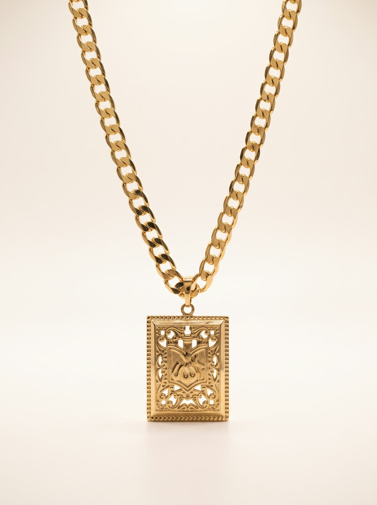 Cadena cubana con dije Heritage Crest en baño de oro de 14 quilates, en fotografía de estudio